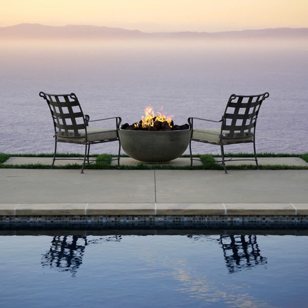 Moderno I Bowl 39-inch round concrete fire pit table by Prism Hardscapes in outdoor patio setting