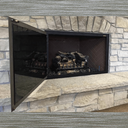 Mission Hidden Main Frame single panel glass fireplace door with left-side hinges installed on stone masonry fireplace