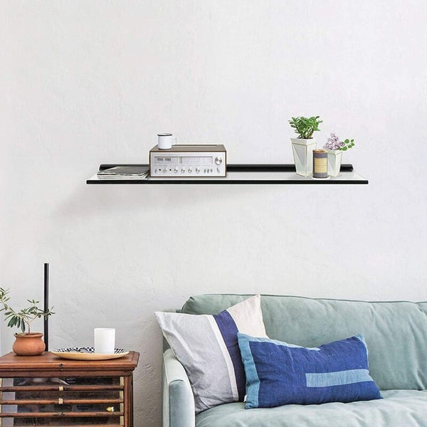 Modern living room with black glass floating mantel shelf displaying a radio and plants above a blue couch and wooden side table