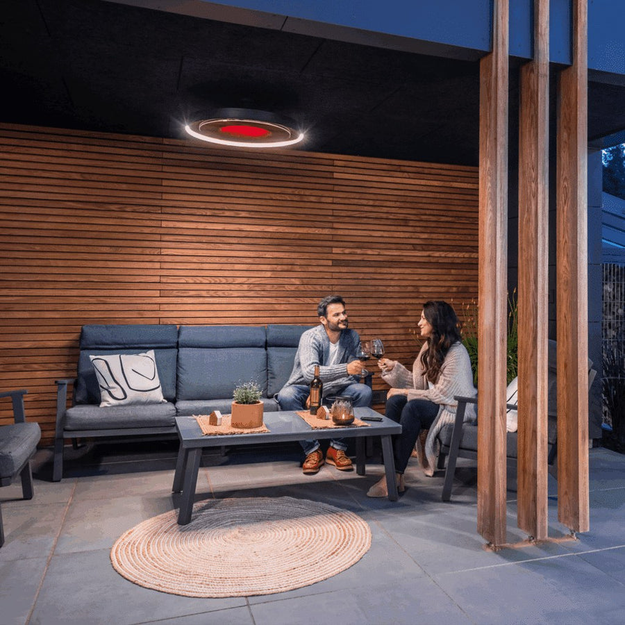 A circular Eclipse heater and its light above an outdoor sofa at dusk