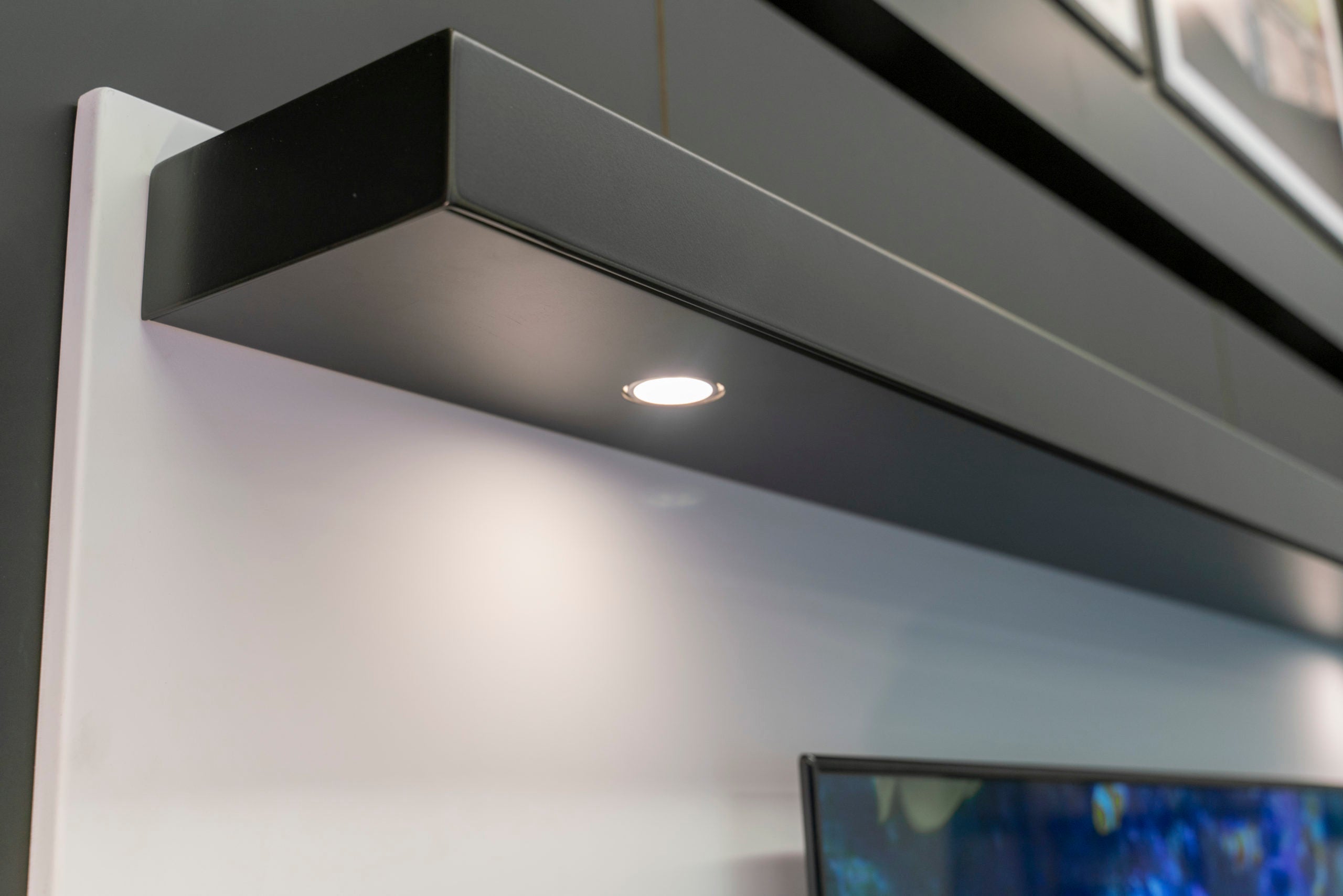 Stoll metal shelf with lighting illuminating the fireplace wall below
