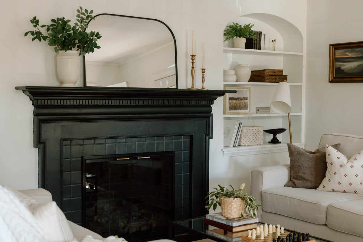 Glass fireplace doors in a dark surround, with white built-in shelving and neutral seating