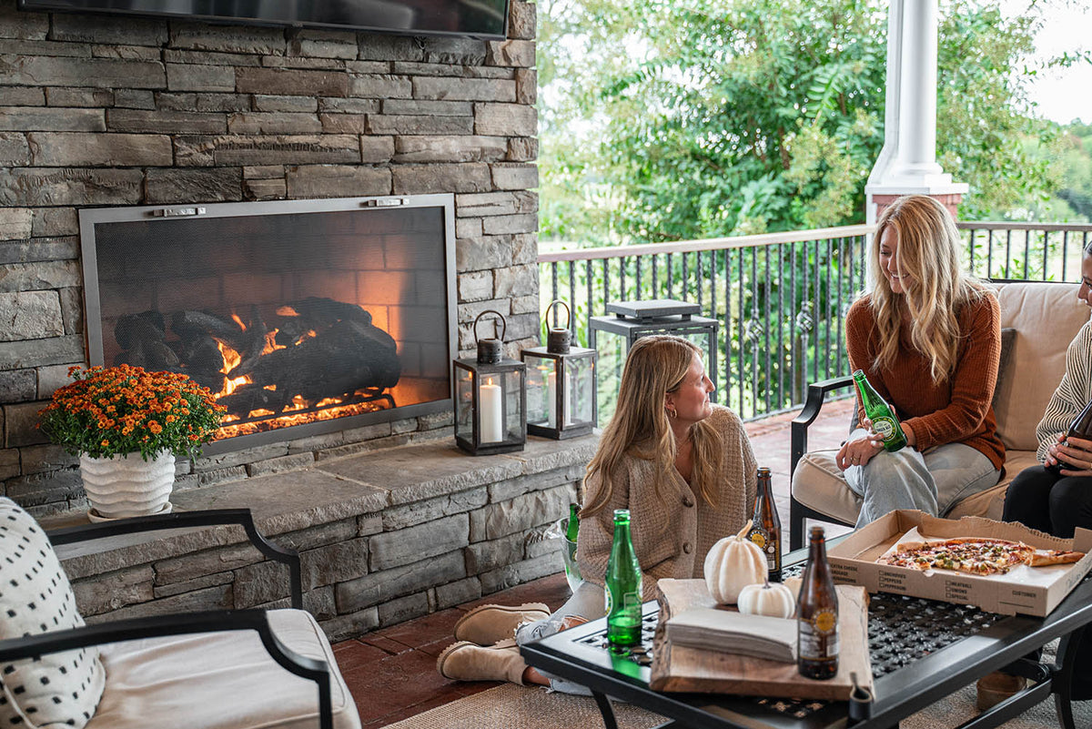 Metal mesh fireplace screen in a stone fireplace on a covered porch with people seated nearby